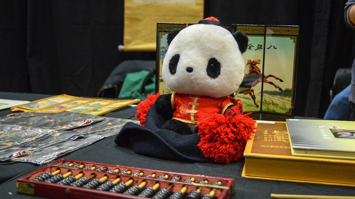 几本关于中国的书, 还有一个穿着传统服装的熊猫毛绒玩具, an abacus, 以及描绘田野里一匹马的面板艺术品.  