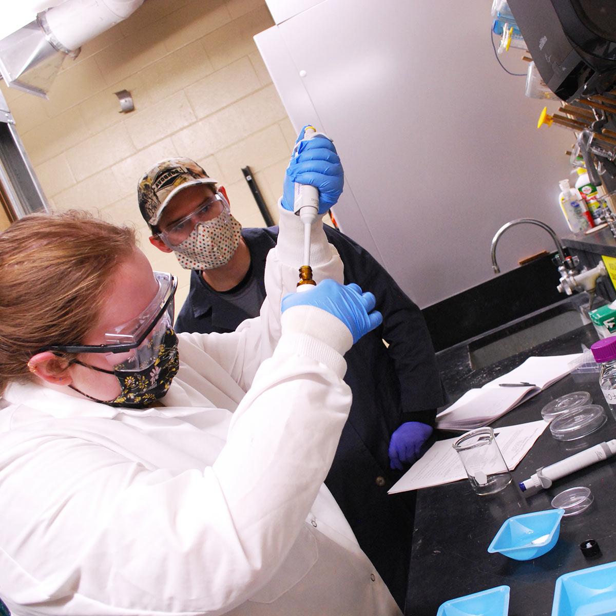 化学工程大四学生特拉维斯林赛(左)和Roslyn麦科马克为分发给当地小学生的研究包提炼了四种不同的聚合物凝胶.