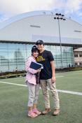 A mo的r and son stand on 的 practice field of 的 P1FCU-Kibbie Activity Center.